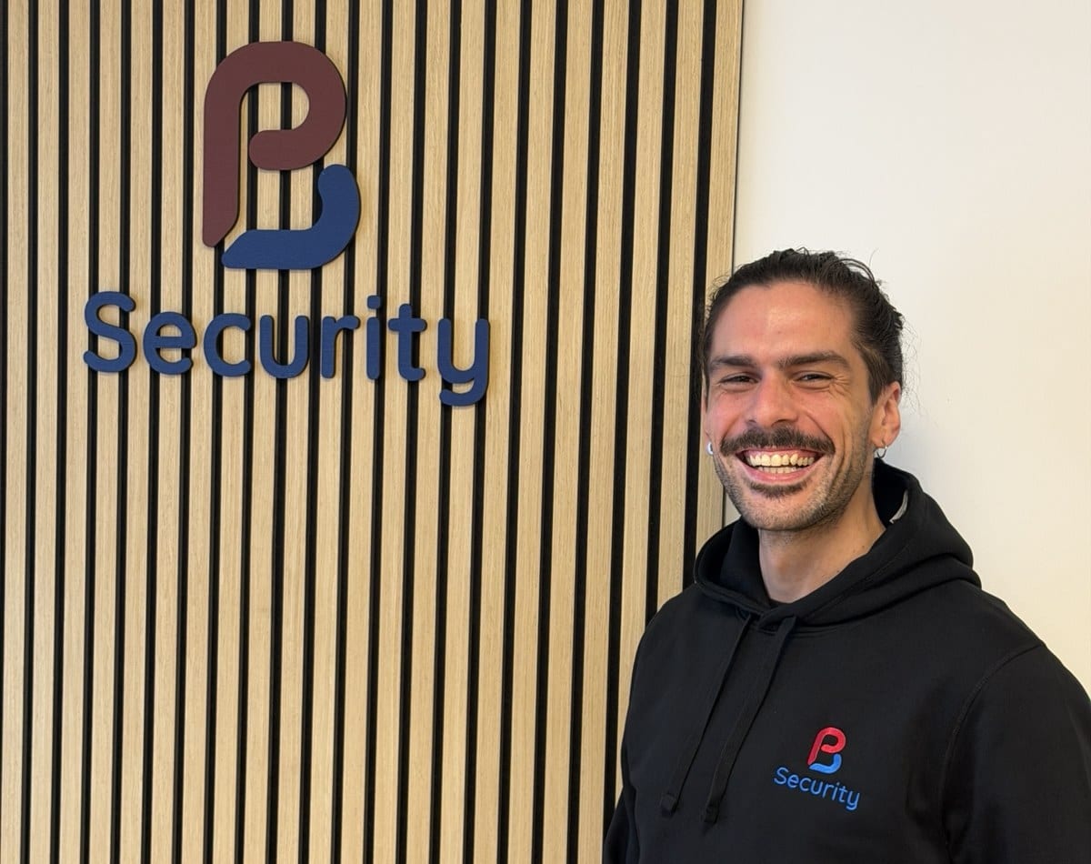 Jonathan står ved PB Security-skiltet på kontoret i en PB Security-hættetrøje